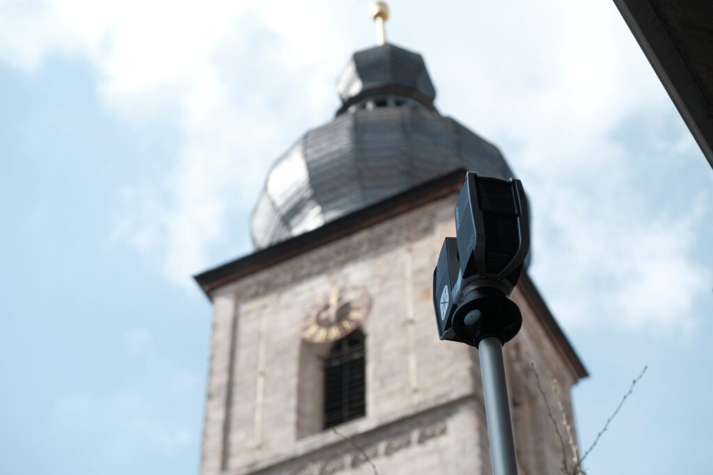 laserscanner-kirche-sankt-martin Laserscanner auf dem Stativ vor der Kirche St. Martin, der Turm im Gegenlicht dahinter.