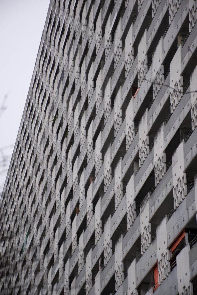 wohnhochhaus-fassade-bestand Fassade eines Wohnhochhauses im Bestand, von unten aufgenommen: gleichförmige Balkonreihen mit verwitterten Betonbrüstungen.